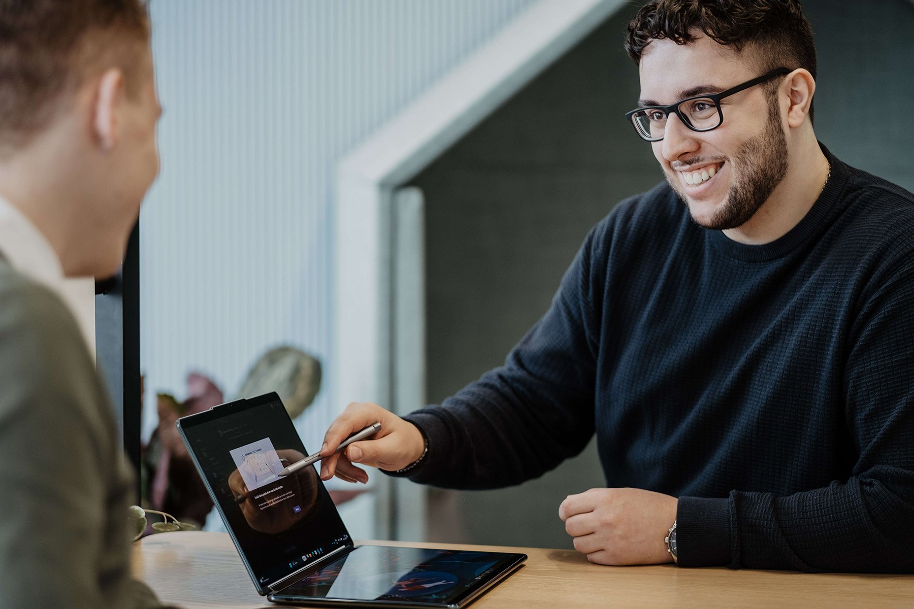 Employee is showing someone something on his laptop during a meeting