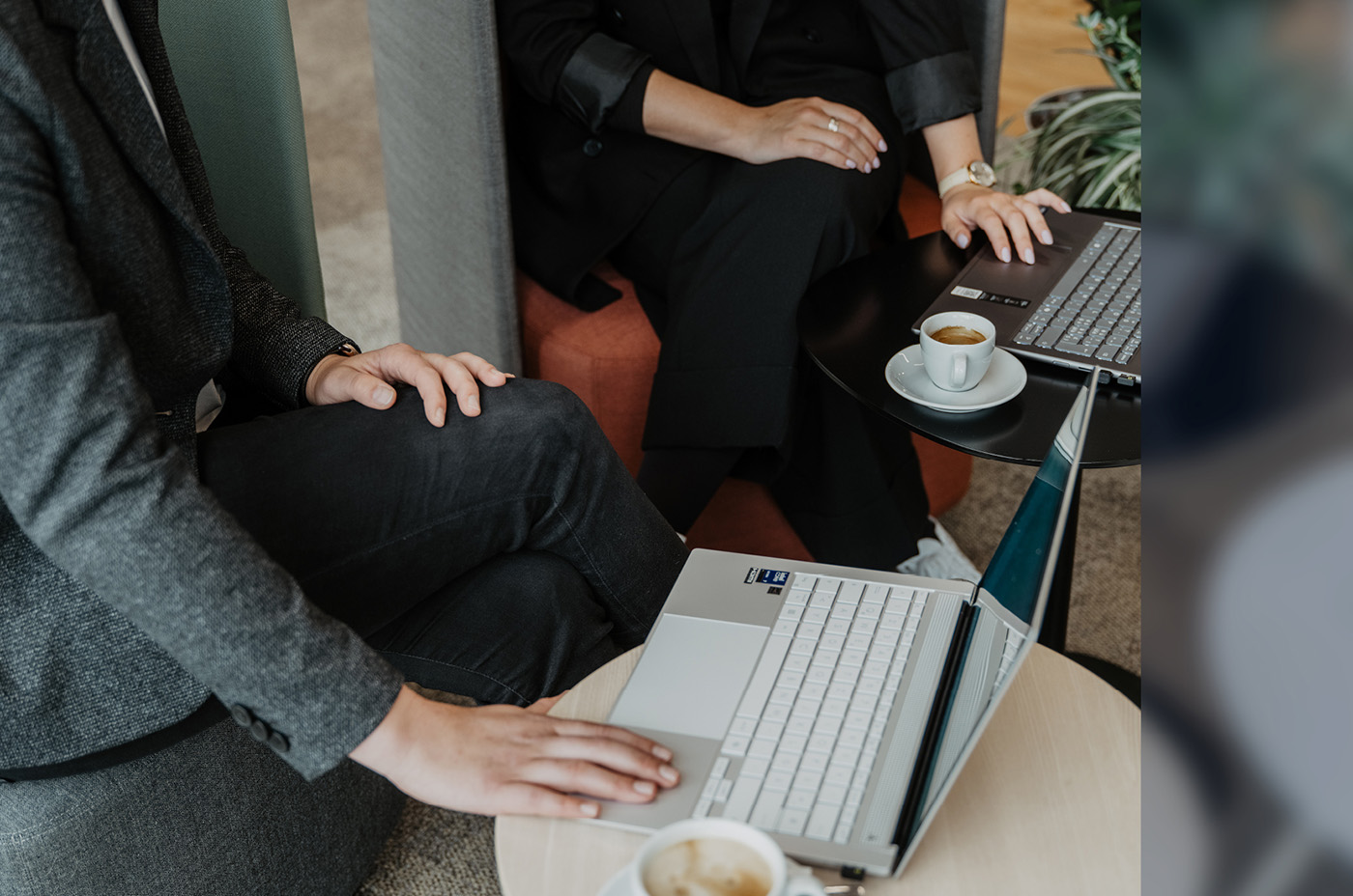 Two employees with laptops and coffee in the lounge (close-up)